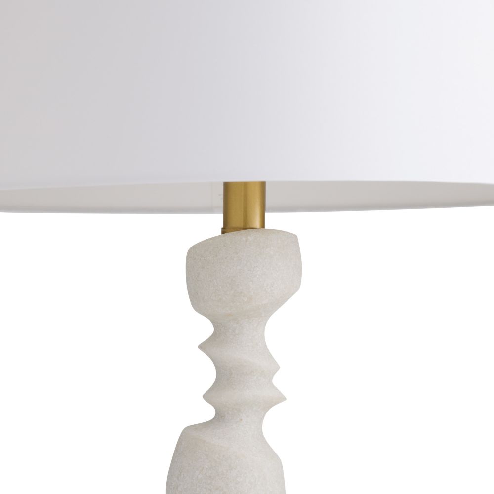 Lamp with a textured white base and gold fixture on a white background