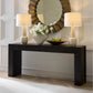 Console table with two lamps and a decorative mirror in a room setting.