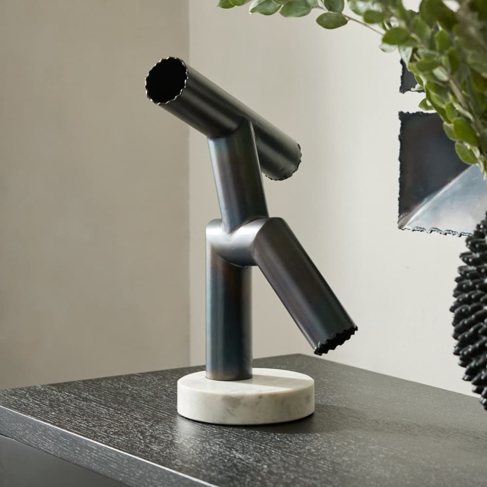 Modern black sculpture on a marble base with a neutral background