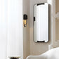 Modern wall-mounted mirror with black frame in a room setting