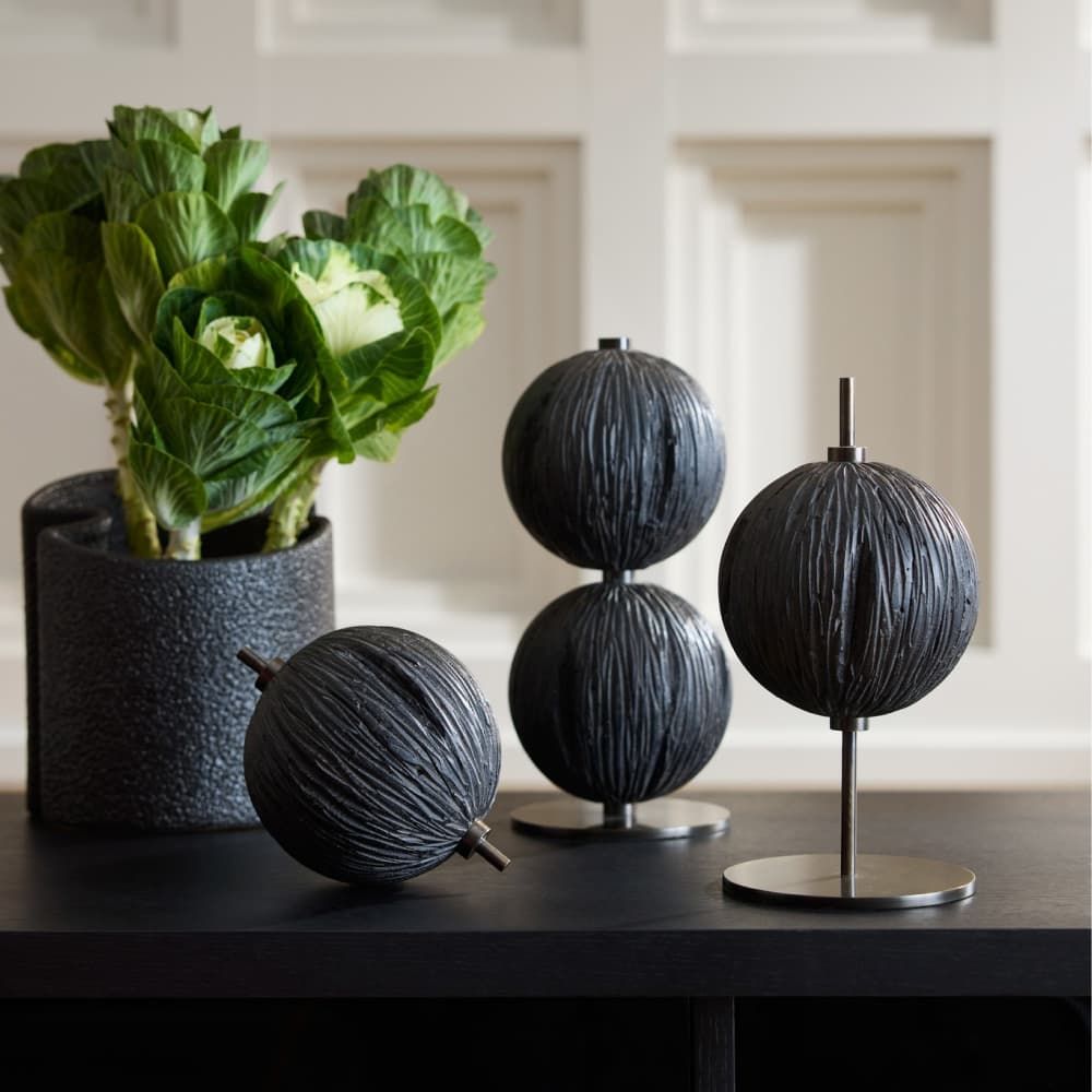 Black spherical decorative items on a table with a plant in the background