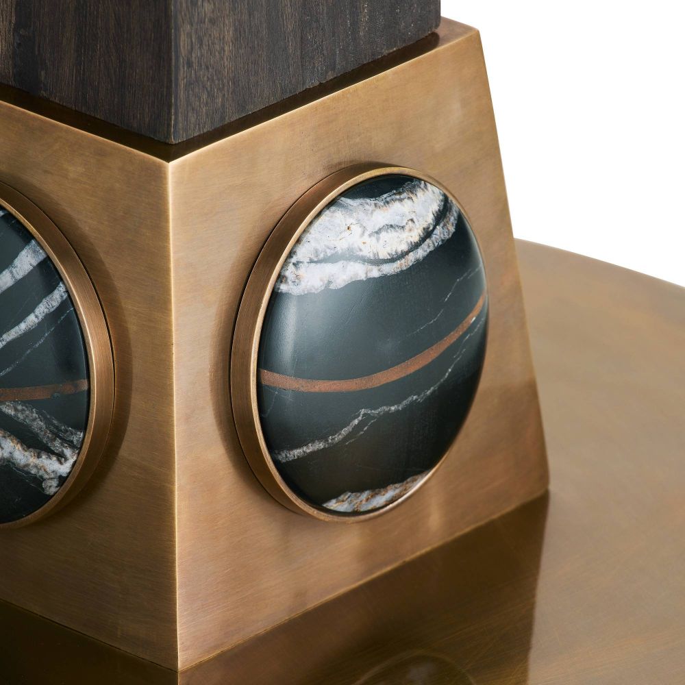 Decorative object with bronze frame and circular black and white stone inlays on a wooden surface.