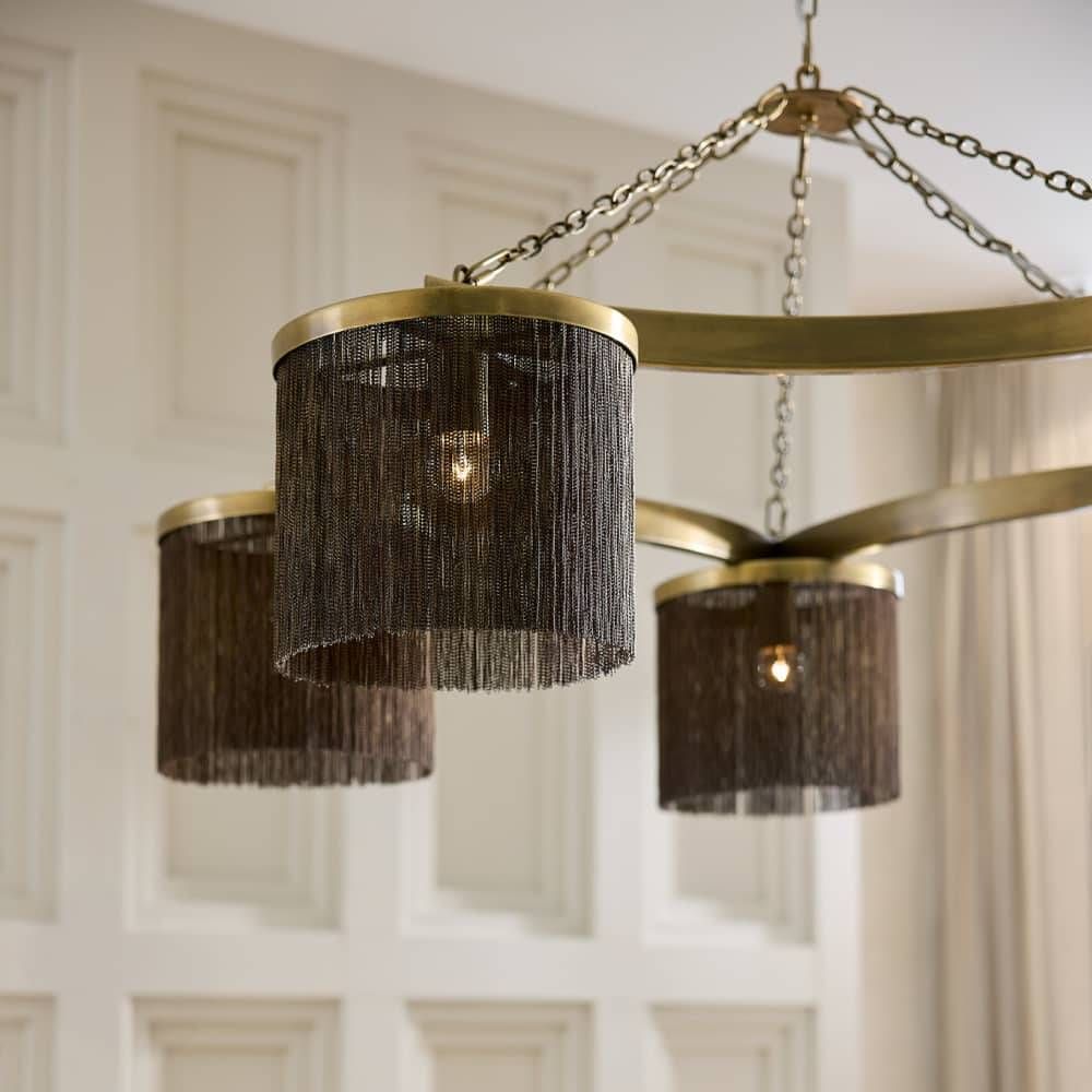 Chandelier with gold frame and black lampshades against a white wall.