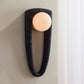 Modern wall sconce with black textured fixture and white bulb on a neutral wall.