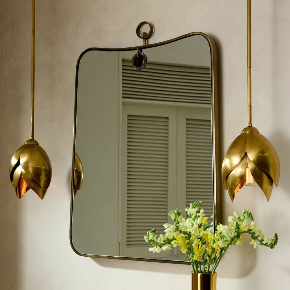 Decorative wall mirror with gold frame and hanging lights on a neutral wall.