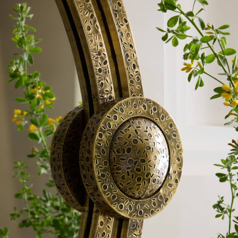 Decorative brass ring with intricate patterns against a blurred natural background