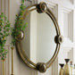 Decorative round mirror with ornate frame on a wall with plants and decor items.
