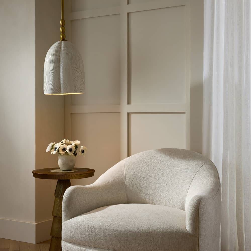 Beige armchair in a room with a small wooden table and decorative vase.