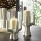Decorative candle holders with candles on a surface, with a blurred natural background