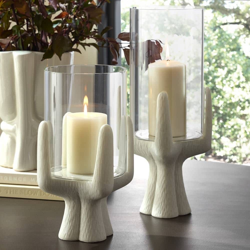 Decorative candle holders with candles on a surface, with a blurred natural background