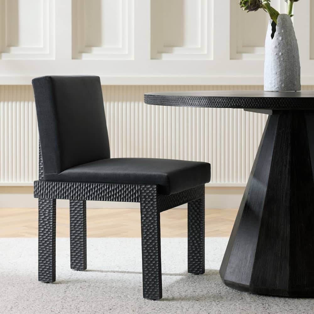 Black dining chair next to a black dining table with a vase on it.