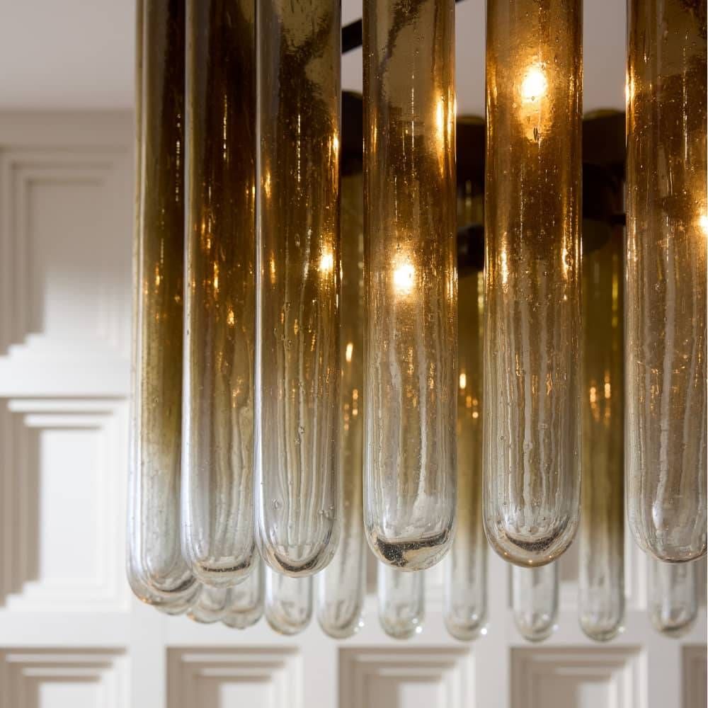 Close-up of a modern chandelier with glass tubes against a neutral background