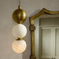 Decorative pendant light with spherical bulbs hanging against a neutral wall.