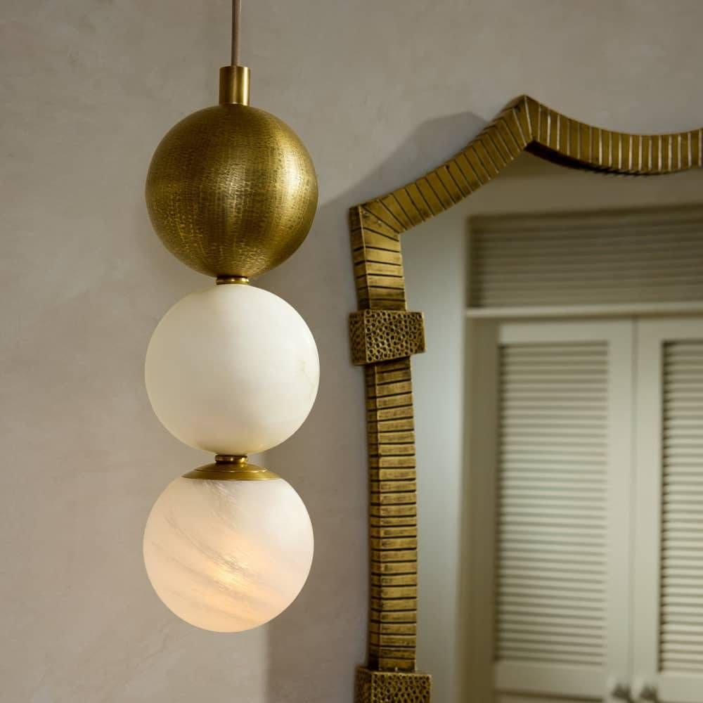 Decorative pendant light with spherical bulbs hanging against a neutral wall.