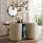 Modern dining room with round mirror, chandelier, and upholstered chairs.