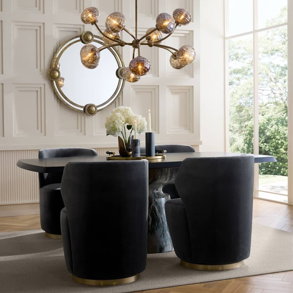 Dining room with a round table and black chairs, featuring a chandelier and decorative elements.