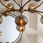 Close-up of a chandelier with glass shades against a neutral wall.