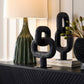 Decorative black cactus sculptures on a shelf with a lamp and plant in the background.