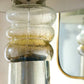 Clear glass vase with ribbed design next to a mirror