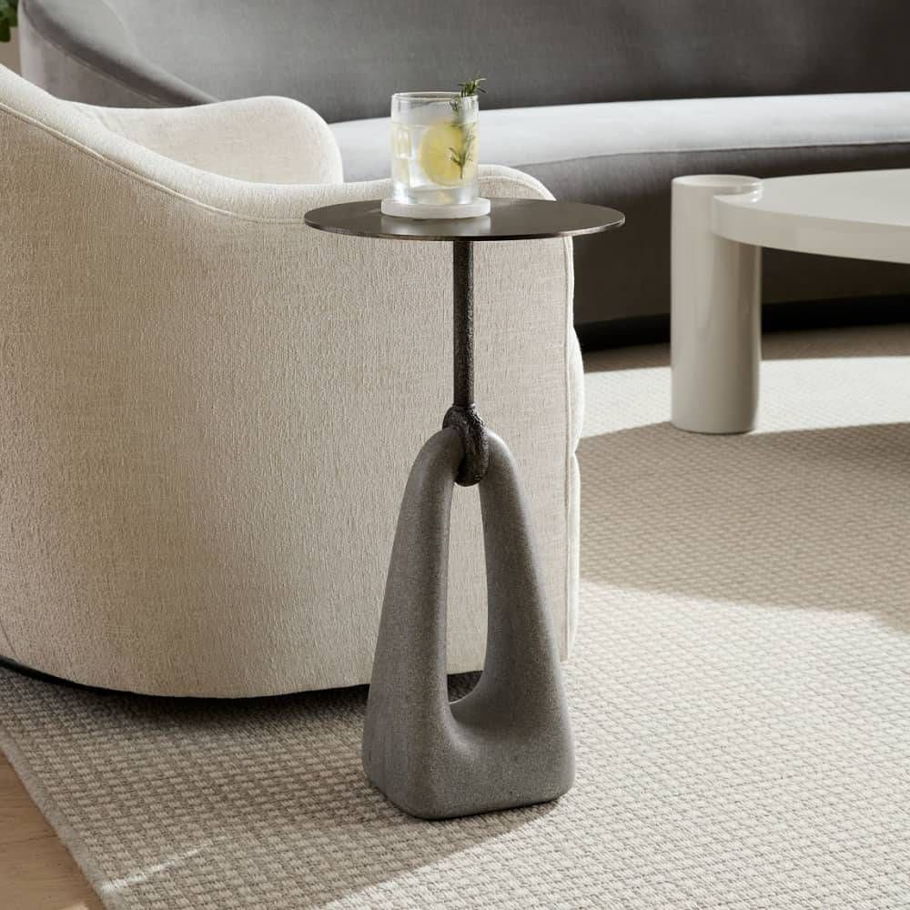 Small side table with a glass of water on a modern living room floor.