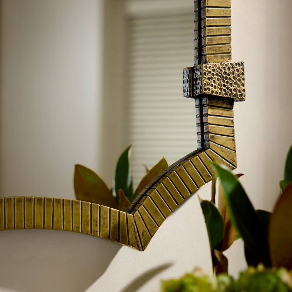 Decorative wall mirror with a textured gold frame on a neutral background