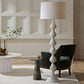 Decorative floor lamp in a living room setting with a chair and tables.