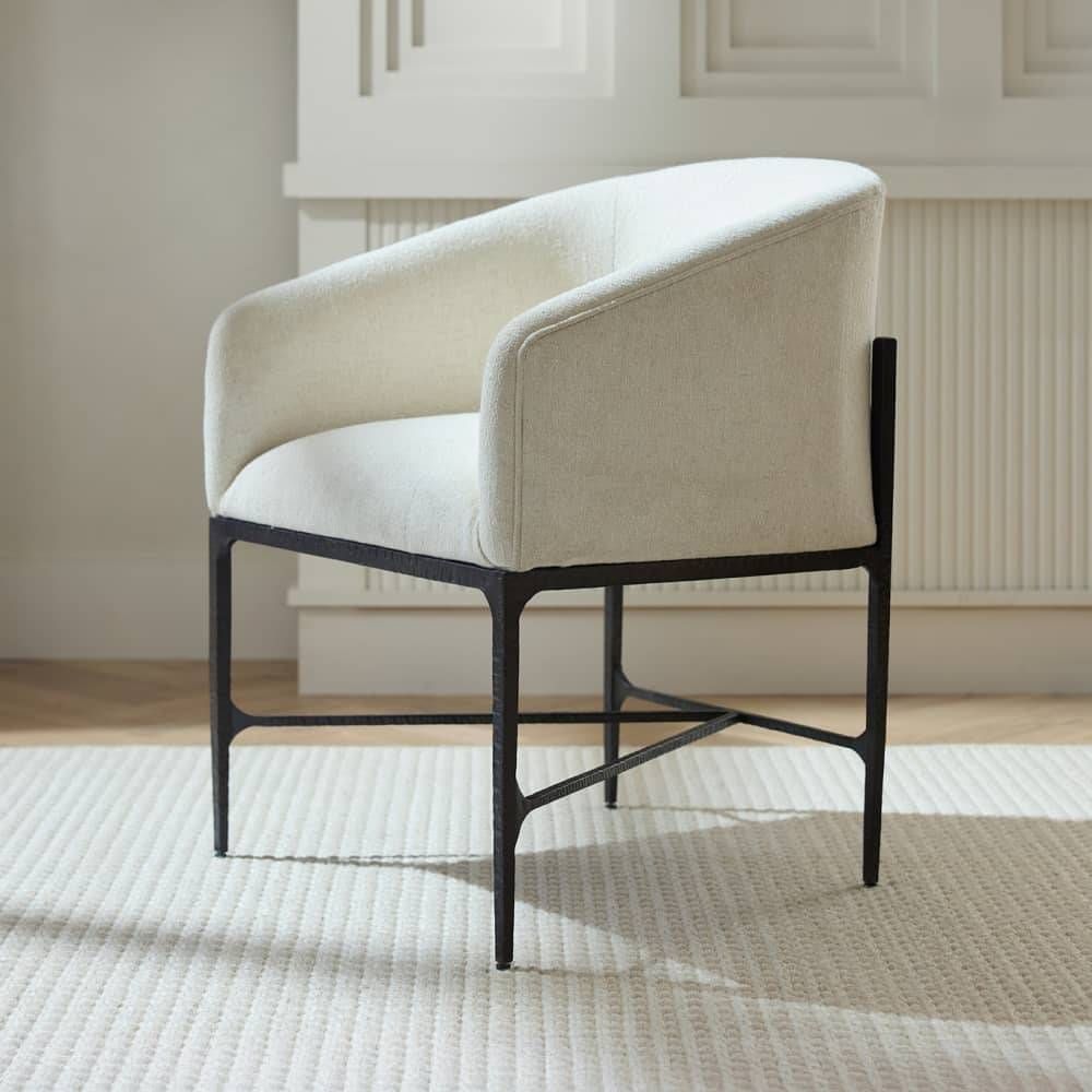 Beige armchair with black metal frame on a textured rug