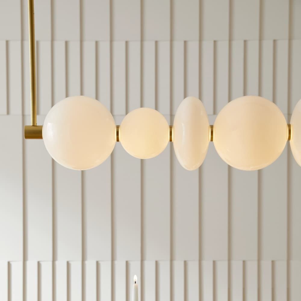 Modern pendant light with round glass shades on a white paneled wall.