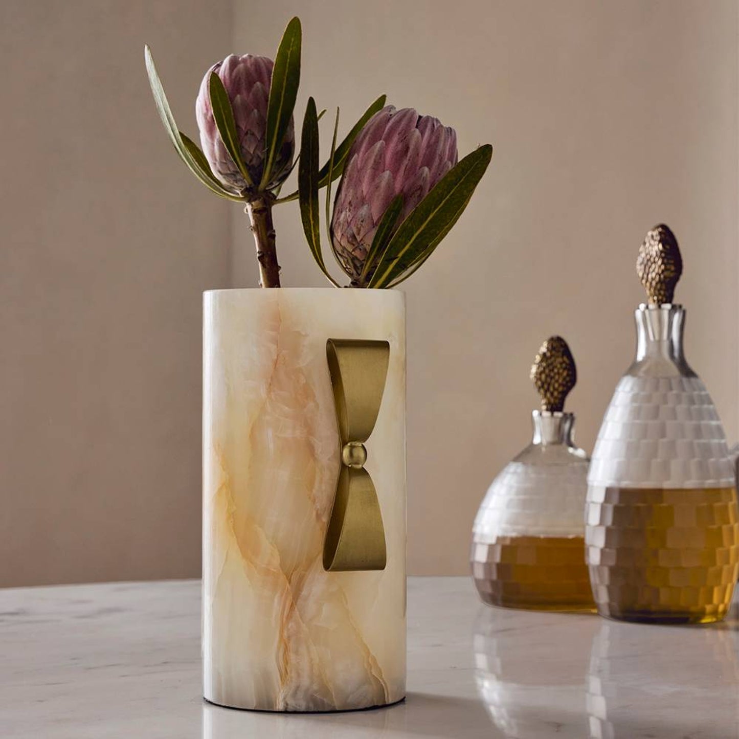 Marble-patterned vase with flowers on a table next to decorative bottles.