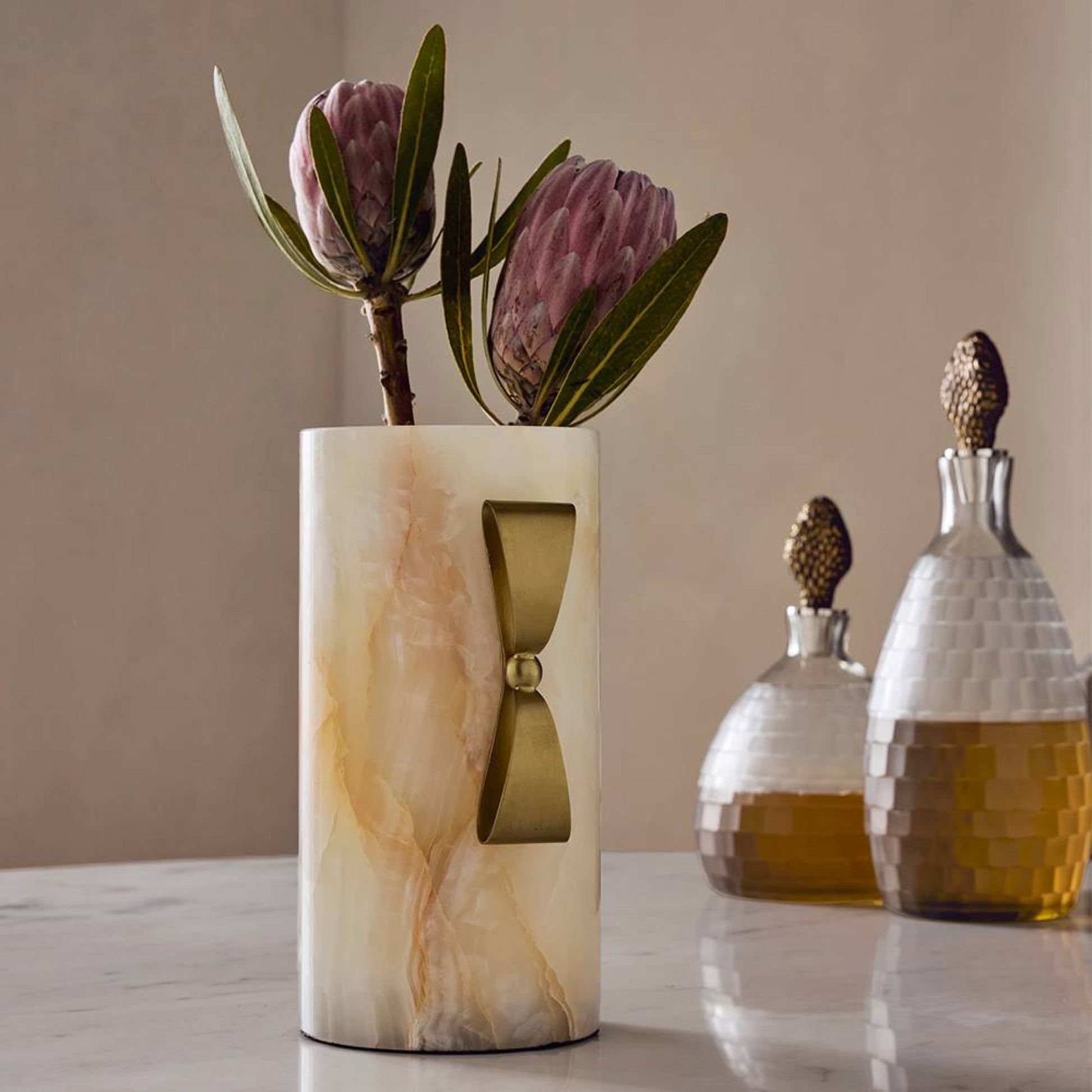 Marble-patterned vase with flowers on a table next to decorative bottles.