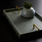 Gray tray with gold handles and a decorative pot on a dark background