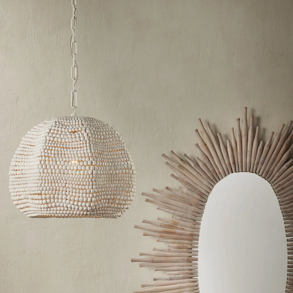 Decorative pendant light and round mirror with wooden frame on a beige wall.