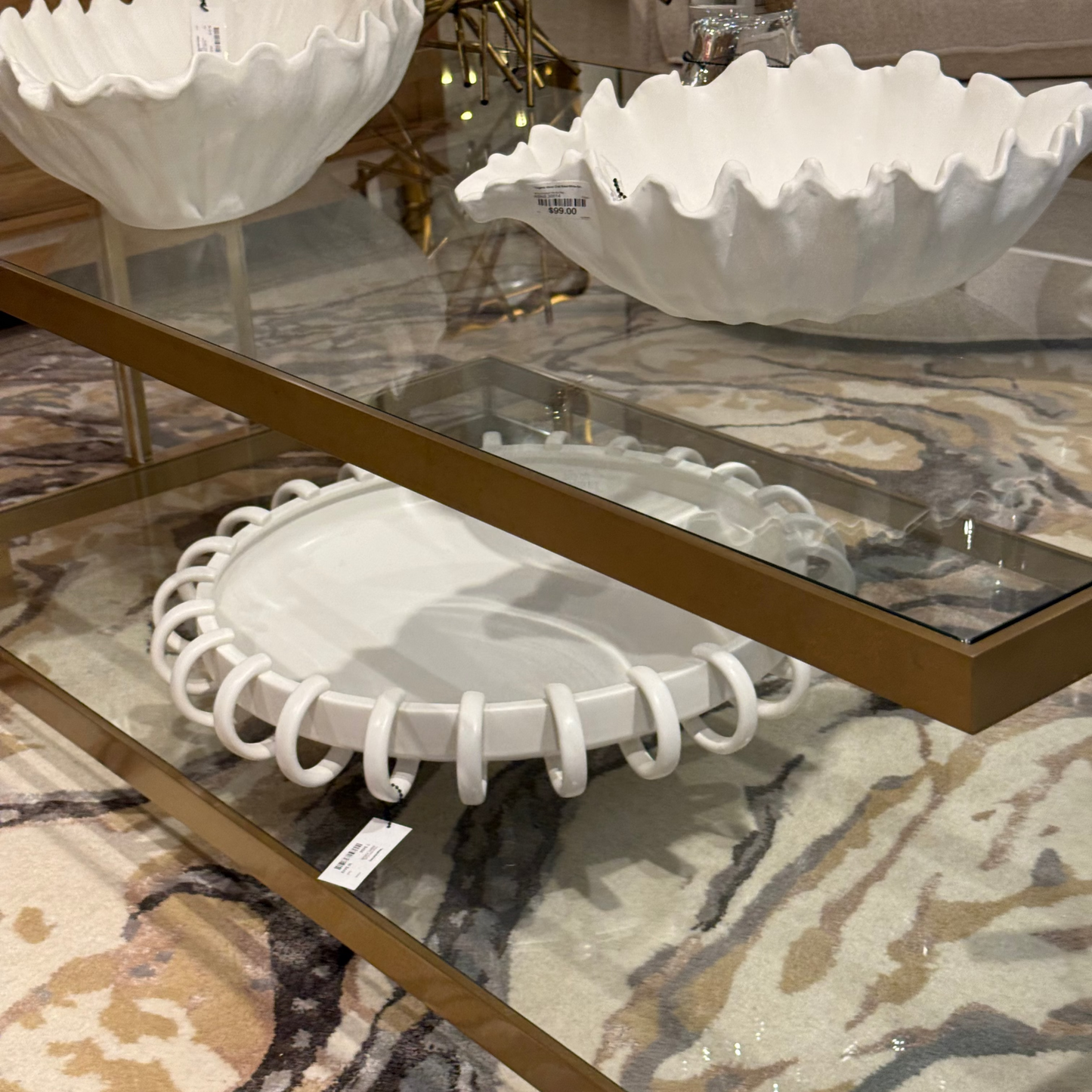 Decorative white ceramic bowls on a glass table with a patterned rug underneath.