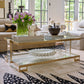 Living room with a glass coffee table, decorative items, and a rug.