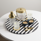 Decorative tray with striped pattern, candles, and small bowls on a white surface.