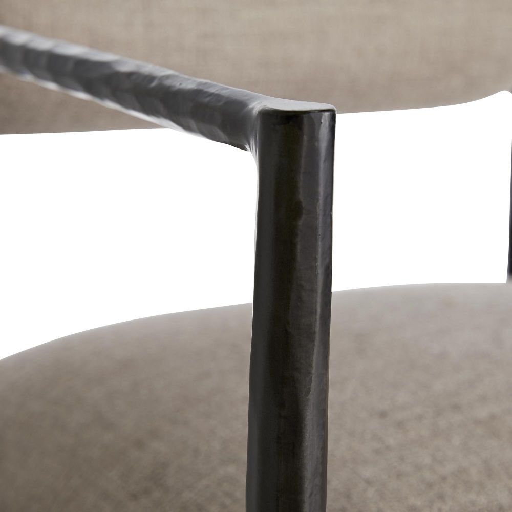 Close-up of a textured metal chair leg with a beige cushioned seat and backrest.