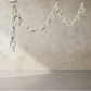 Decorative chain hanging against a textured beige wall