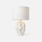 Table lamp with a textured white base and a white shade on a light gray background