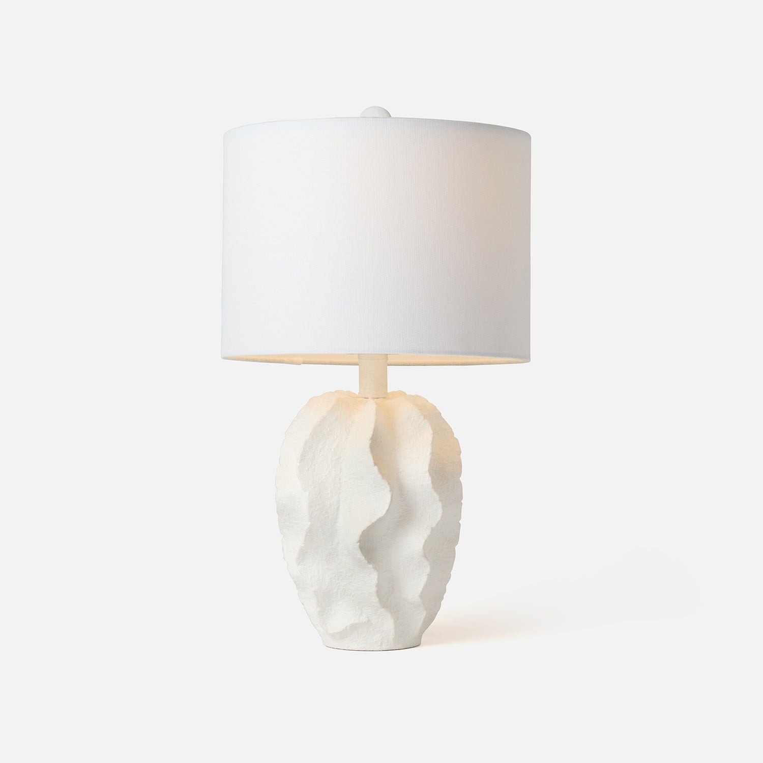 Table lamp with a textured white base and a white shade on a light gray background