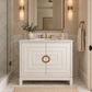 White bathroom vanity with marble top, brass hardware, and black accents in a luxury bathroom