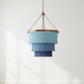 Blue tiered pendant light hanging in a room with white walls and wooden flooring.