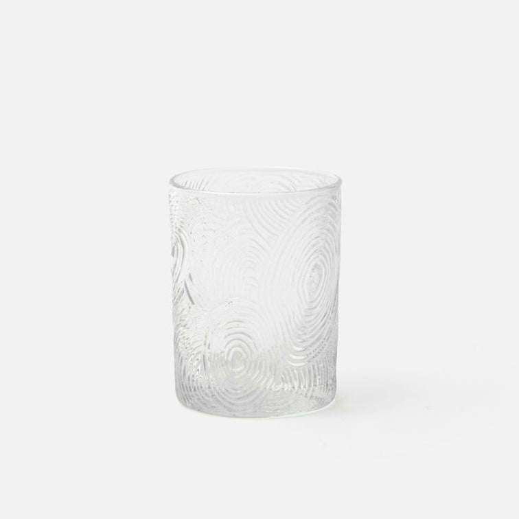 Clear glass tumbler with swirling pattern on a white background