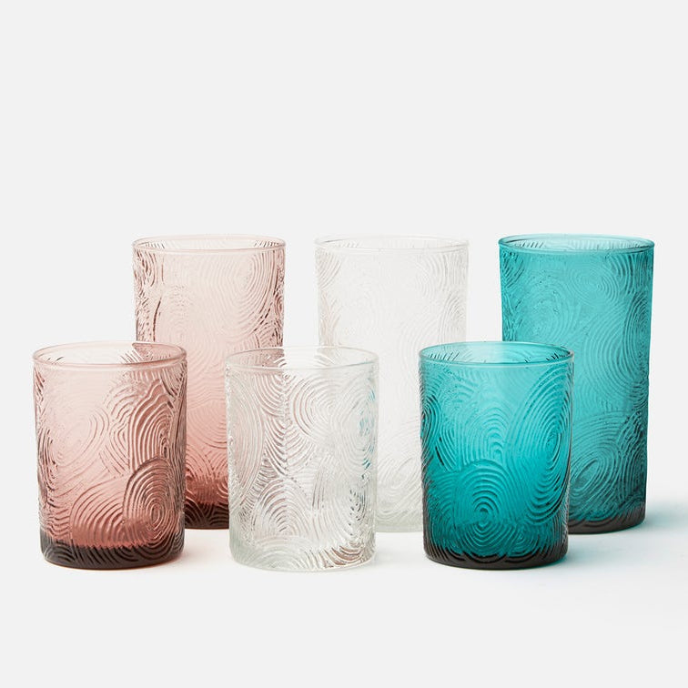 Set of textured glass tumblers in pink, clear, and blue on a white background