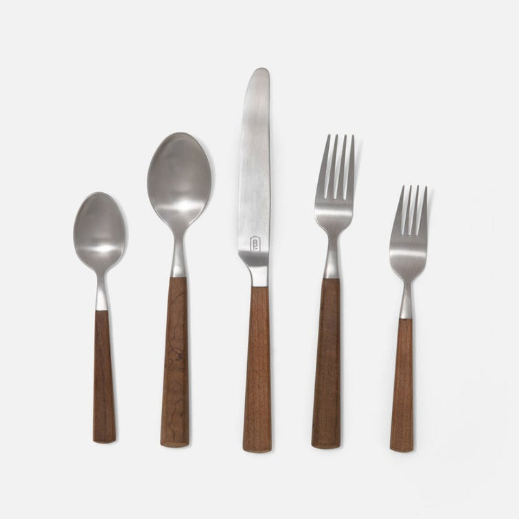 Five-piece flatware set with polished silver metal heads and warm brown wooden handles, arranged vertically on a light gray background.