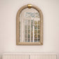 Beige dresser with gold accents and an arched mirror above it against a white paneled wall.