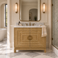 French-inspired bathroom with a natural wood vanity, white marble countertop, brass hardware, crown moulding, and cool-toned marble tile flooring.