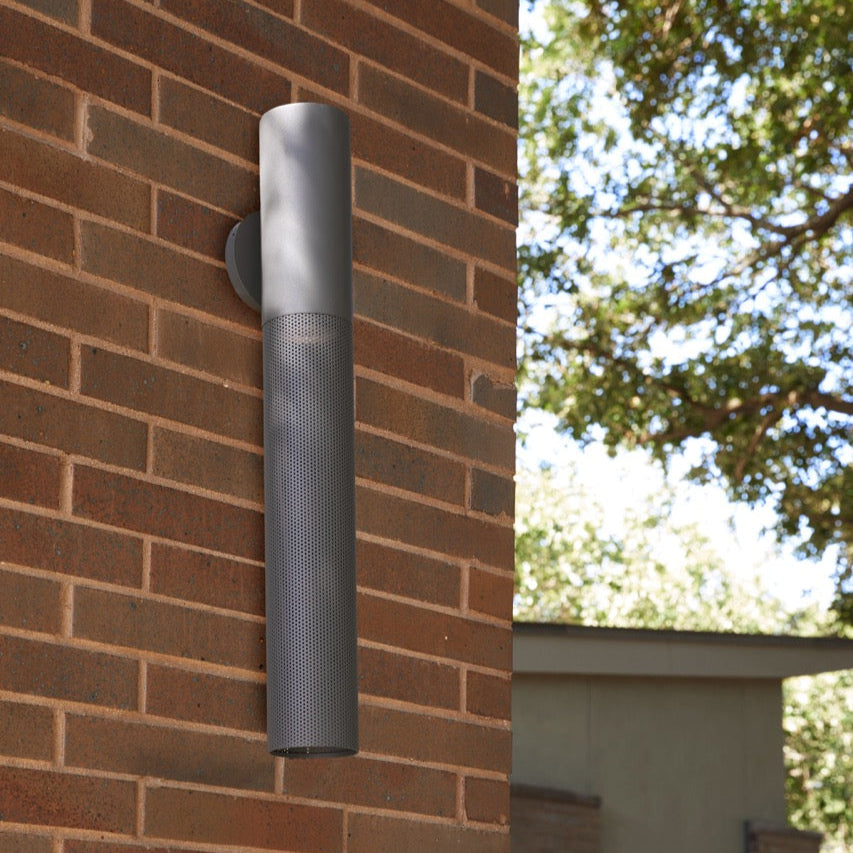Outdoor wall light fixture on a brick wall with trees in the background