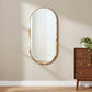 Wooden dresser with a plant and decorative item next to an oval mirror on a beige wall.