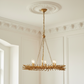 A gold leaf-style chandelier with candle-style bulbs hanging from a decorative ceiling medallion in a white paneled room.