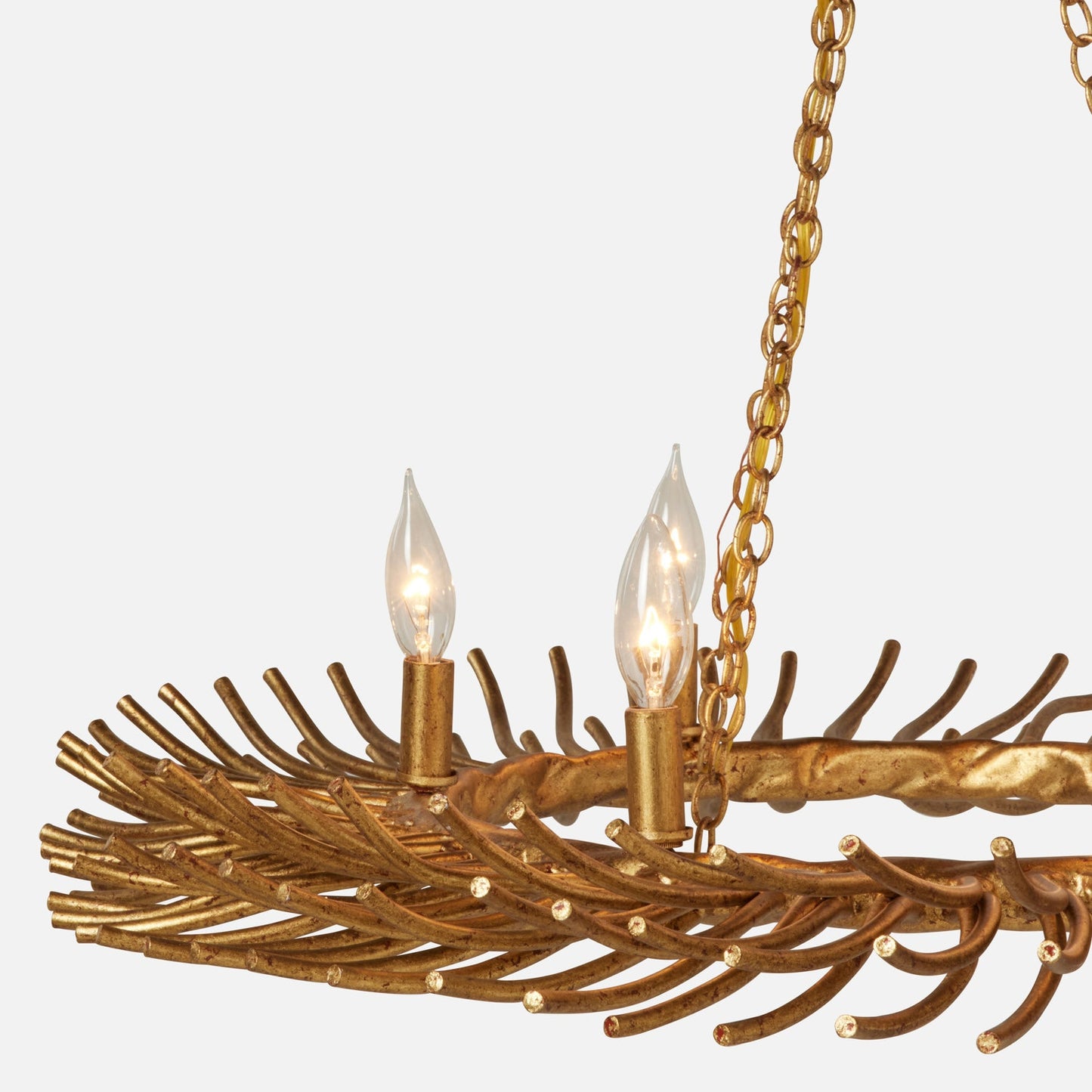 A close-up of a gold-toned branch-style chandelier with two lit candle-style bulbs and a hanging chain against a light gray background.